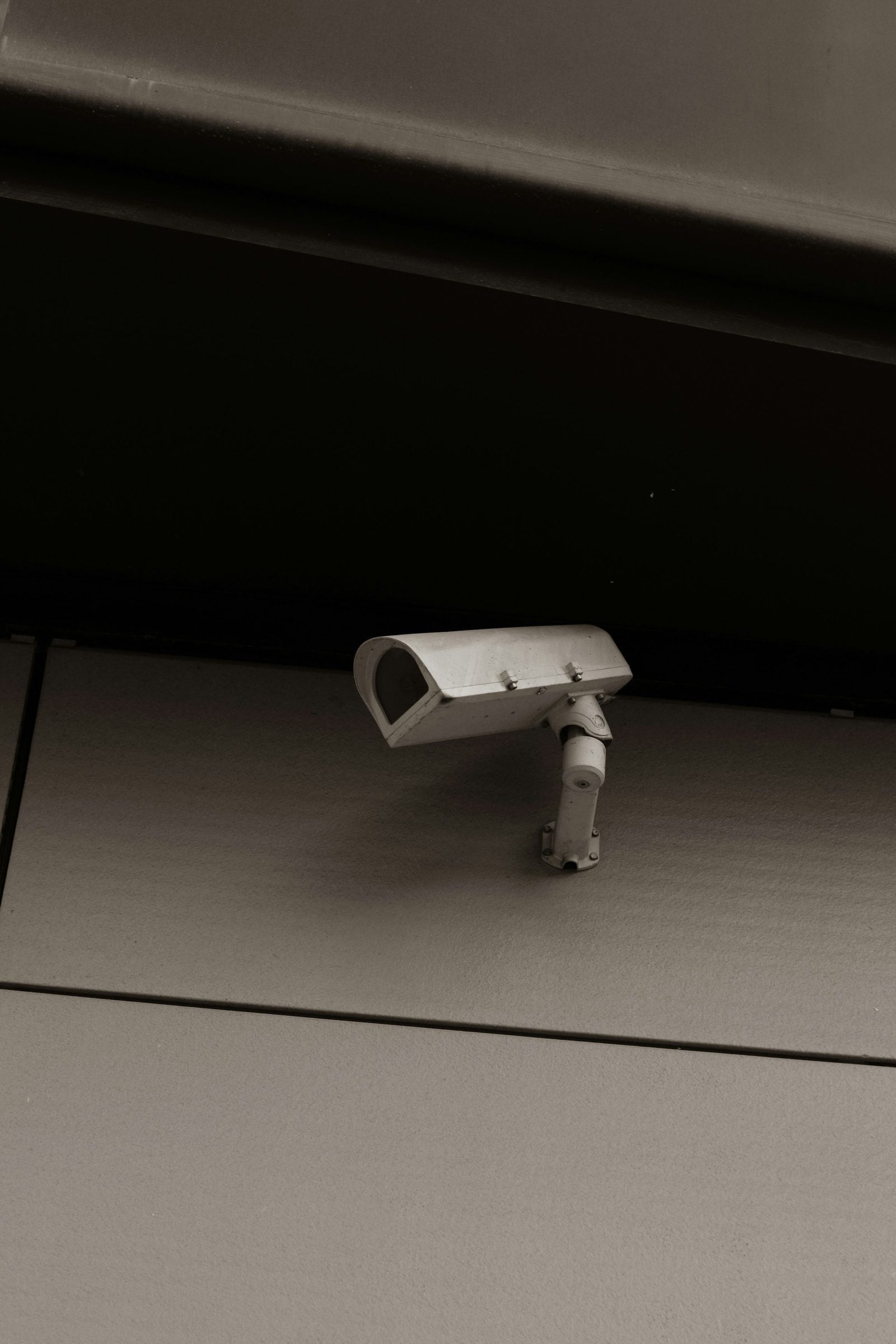 A small security camera mounted under the eave of a building
