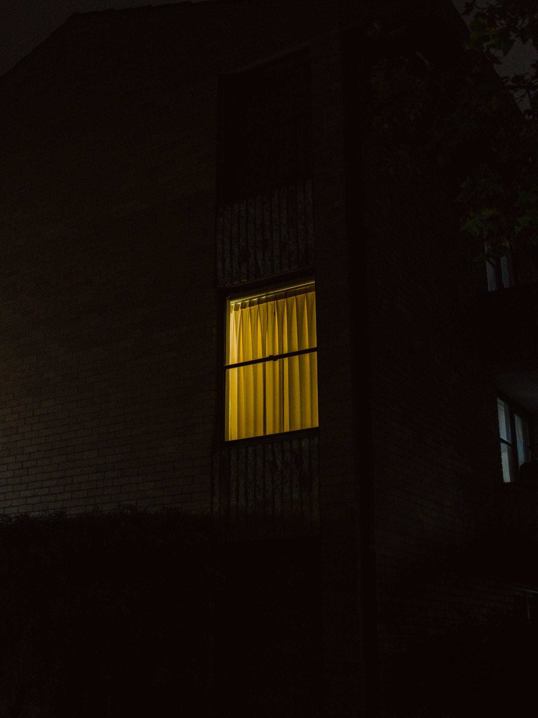 One lit window in an otherwise dark building at night